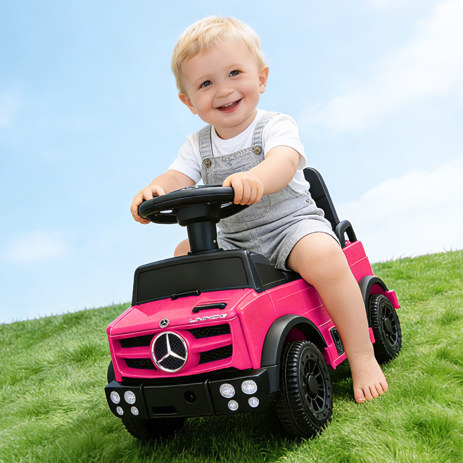 A smiling toddler riding the pink Mercedes-Benz Unimog push car on a green grassy hill, showcasing its anti-slip wheels and sturdy design for safe outdoor adventure and active play.